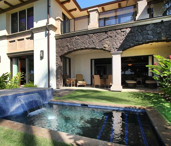 A modern two-story house with a pool, stone accents, and a shaded patio, set in a lush garden. (140 characters).