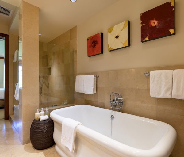The image shows a stylish bathroom featuring a freestanding tub, decorative wall art, and neatly arranged towels.