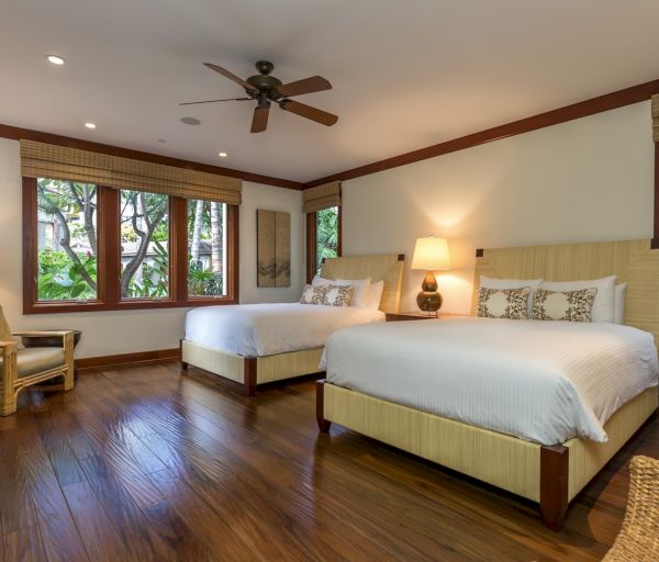 The image shows a cozy bedroom with two beds, wooden floors, and large windows allowing natural light and views.