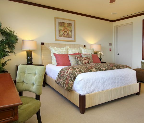 The image features a cozy bedroom with a large bed, decorative pillows, a desk, and a touch of greenery for a homey atmosphere.