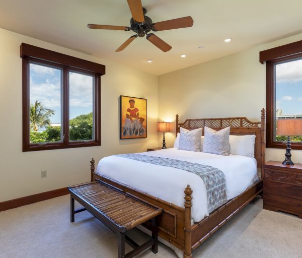 The image shows a cozy bedroom with a bed, bedside tables, and large windows letting in natural light. It's inviting and well-decorated.