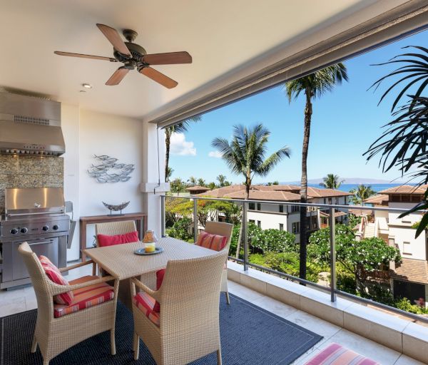 The image features a stylish balcony with dining furniture, a grill, and a picturesque view of palm trees and blue skies.