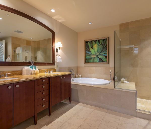 The image depicts a modern bathroom featuring a bathtub, shower, mirror, and elegant cabinetry with warm lighting.